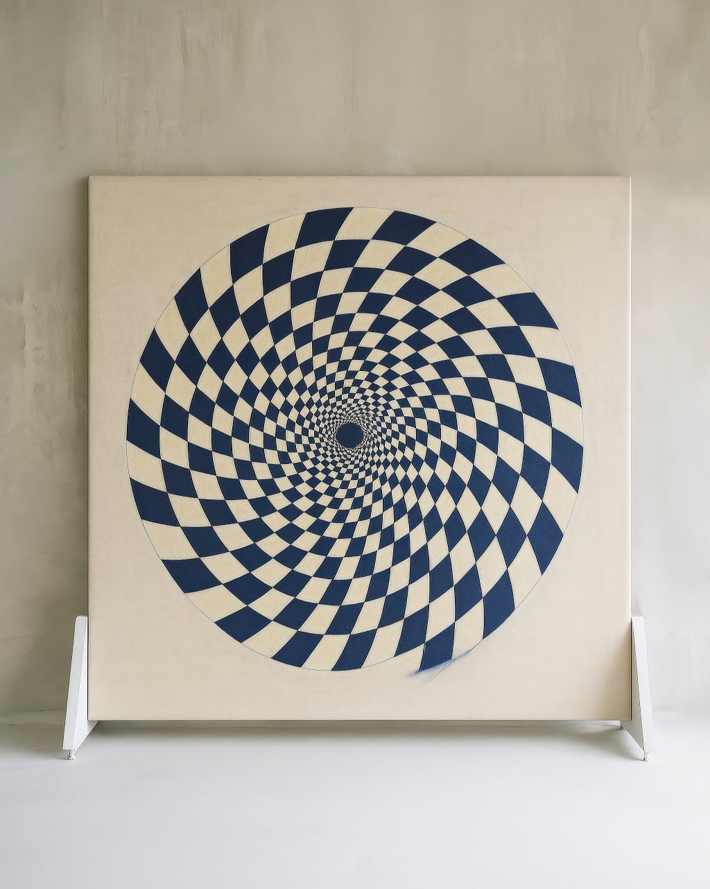 Original medium for Gravity Bloom — a 60-inch canvas painted in indigo and cream, featuring a hypnotic spiral checkerboard design in a minimalist studio setting.